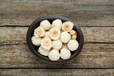 Delicious candies with coconut flakes and hazelnut on wooden table, top view