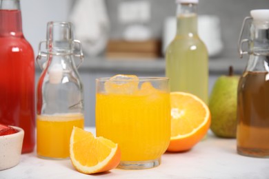 Tasty kombucha in glass, bottles and fresh fruits on white table