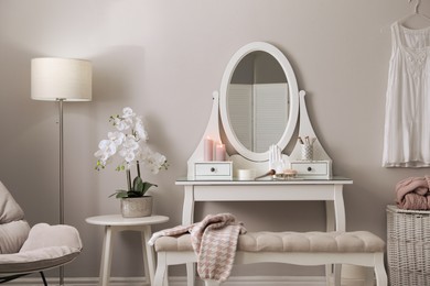 Photo of Wooden dressing table with decorative elements and makeup products in room. Interior design