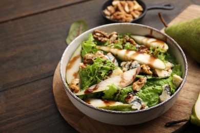 Photo of Delicious pear salad with sauce in bowl on wooden table, closeup. Space for text