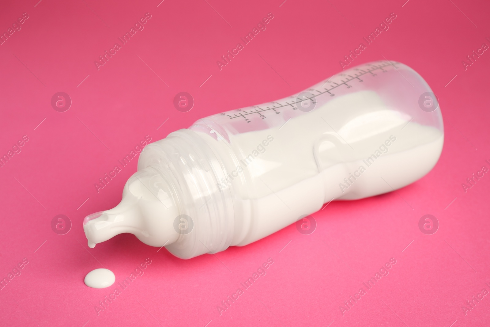 Photo of Feeding bottle with milk on dark pink background