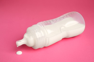 Photo of Feeding bottle with milk on dark pink background