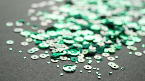 Photo of Pile of beautiful green sequins on black background, closeup