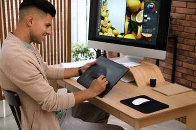 Photo of Professional retoucher working on graphic tablet at desk in office