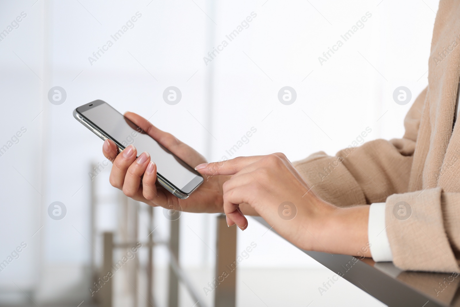 Photo of Young woman using modern smartphone indoors, closeup