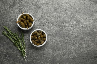 Tasty capers and rosemary on grey table, flat lay. Space for text