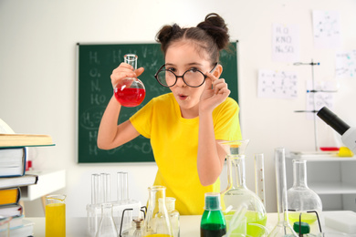 Photo of Schoolchild making experiment at table in chemistry class