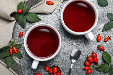 Photo of Fresh rose hip tea and berries on grey table, flat lay
