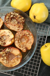 Photo of Tasty baked quinces with walnuts and honey in bowl on black table, flat lay