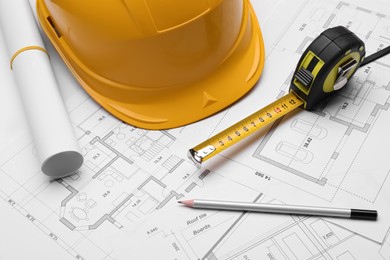 Photo of Pencil, measuring tape and hardhat on blueprints