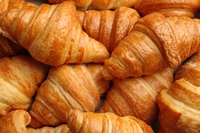 Photo of Fresh tasty croissants as background, closeup. French pastry