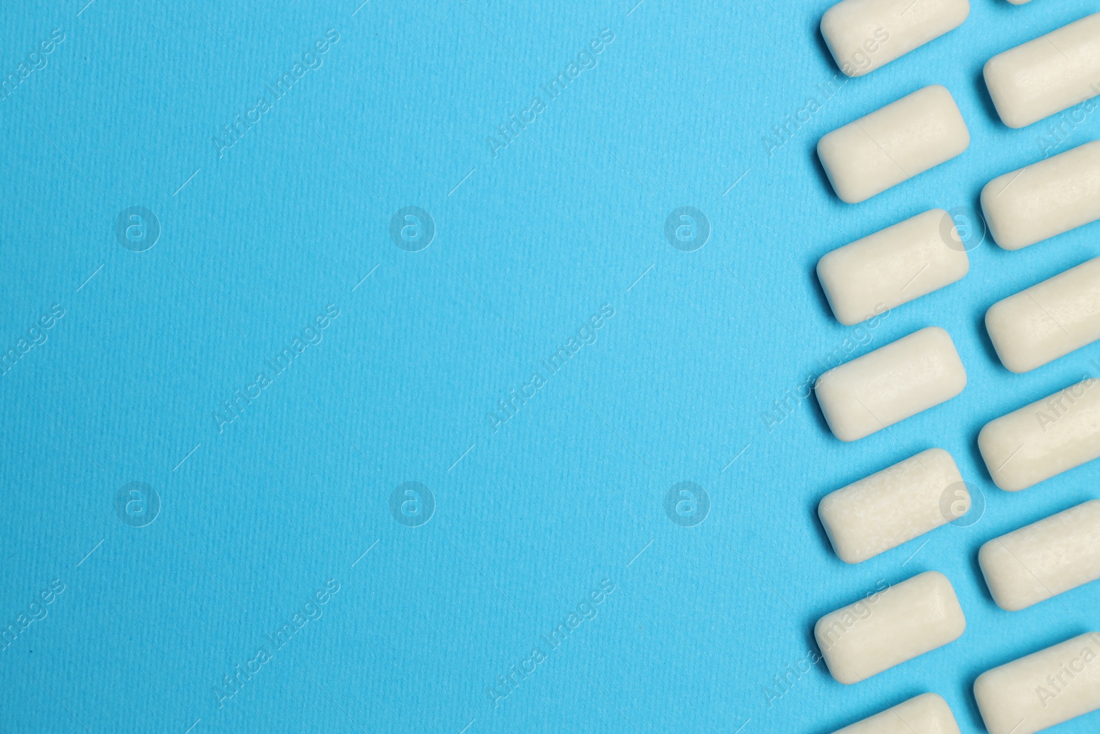 Photo of White bubble gums on blue background, flat lay. Space for text