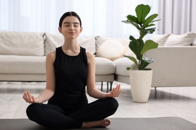 Photo of Beautiful girl meditating on yoga mat at home