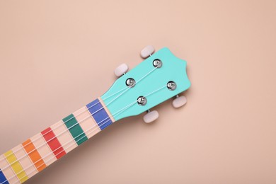 Photo of Colorful ukulele neck on beige background, top view. String musical instrument
