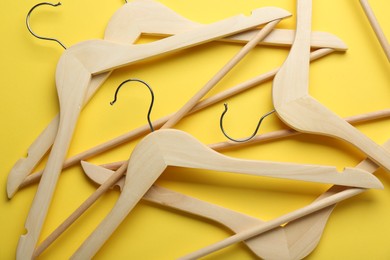 Wooden hangers on yellow background, top view