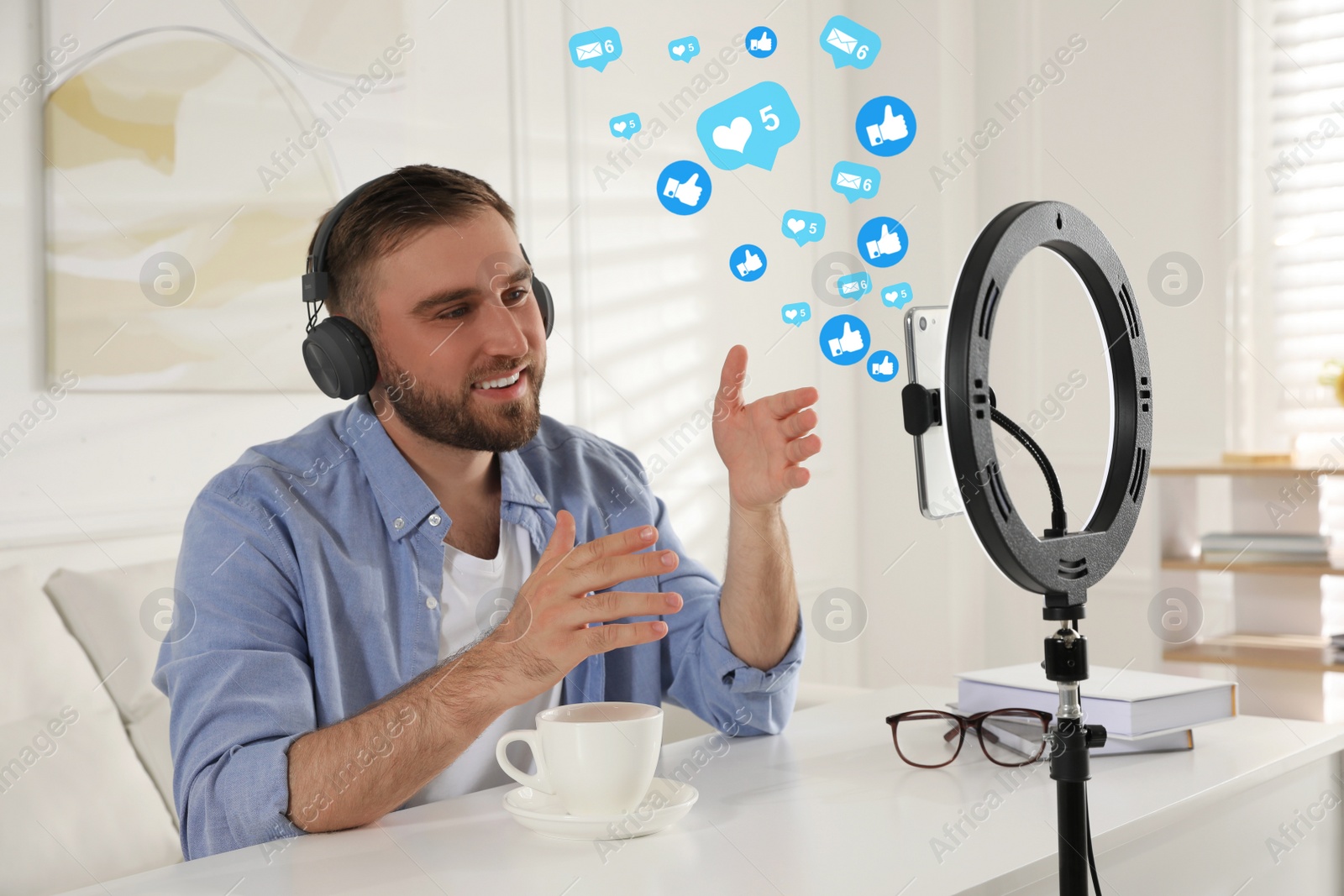 Image of Blogger with cup of tea recording video at table indoors