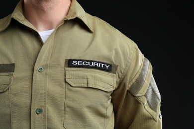 Photo of Male security guard in uniform on dark background, closeup