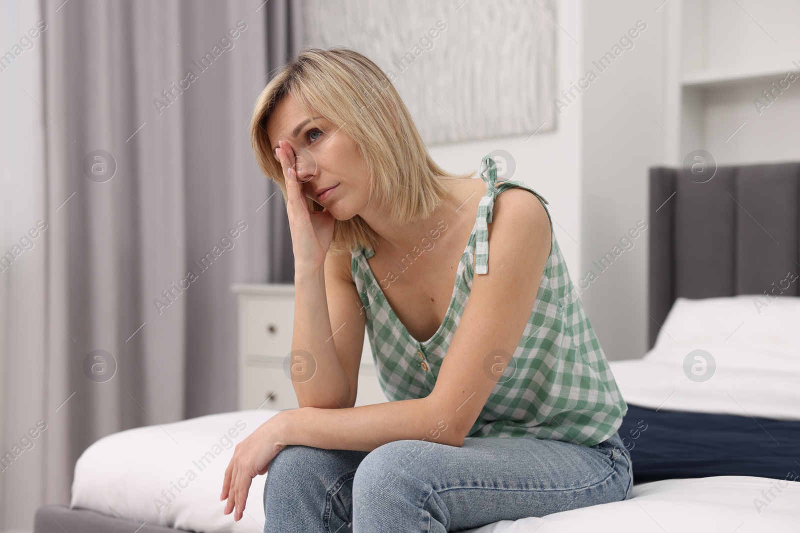 Photo of Overwhelmed woman sitting on bed at home