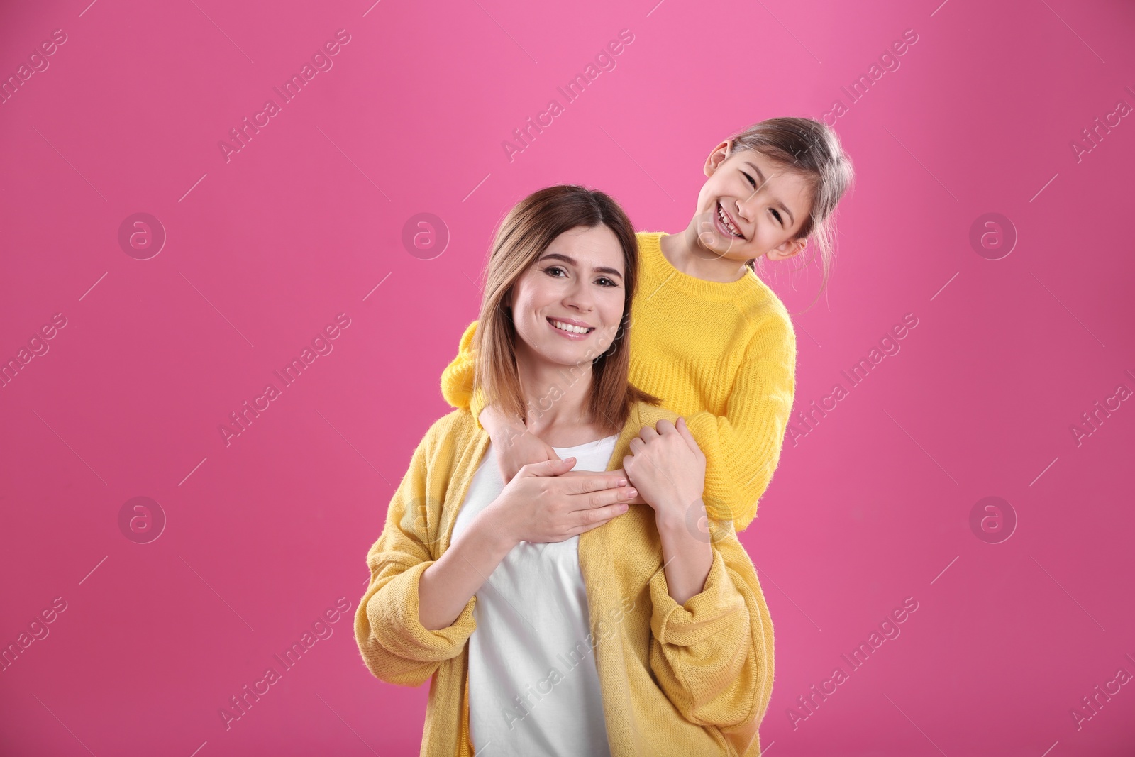 Photo of Happy woman and daughter in stylish clothes on color background