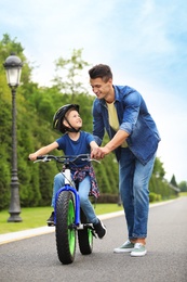 Dad teaching son to ride bicycle outdoors