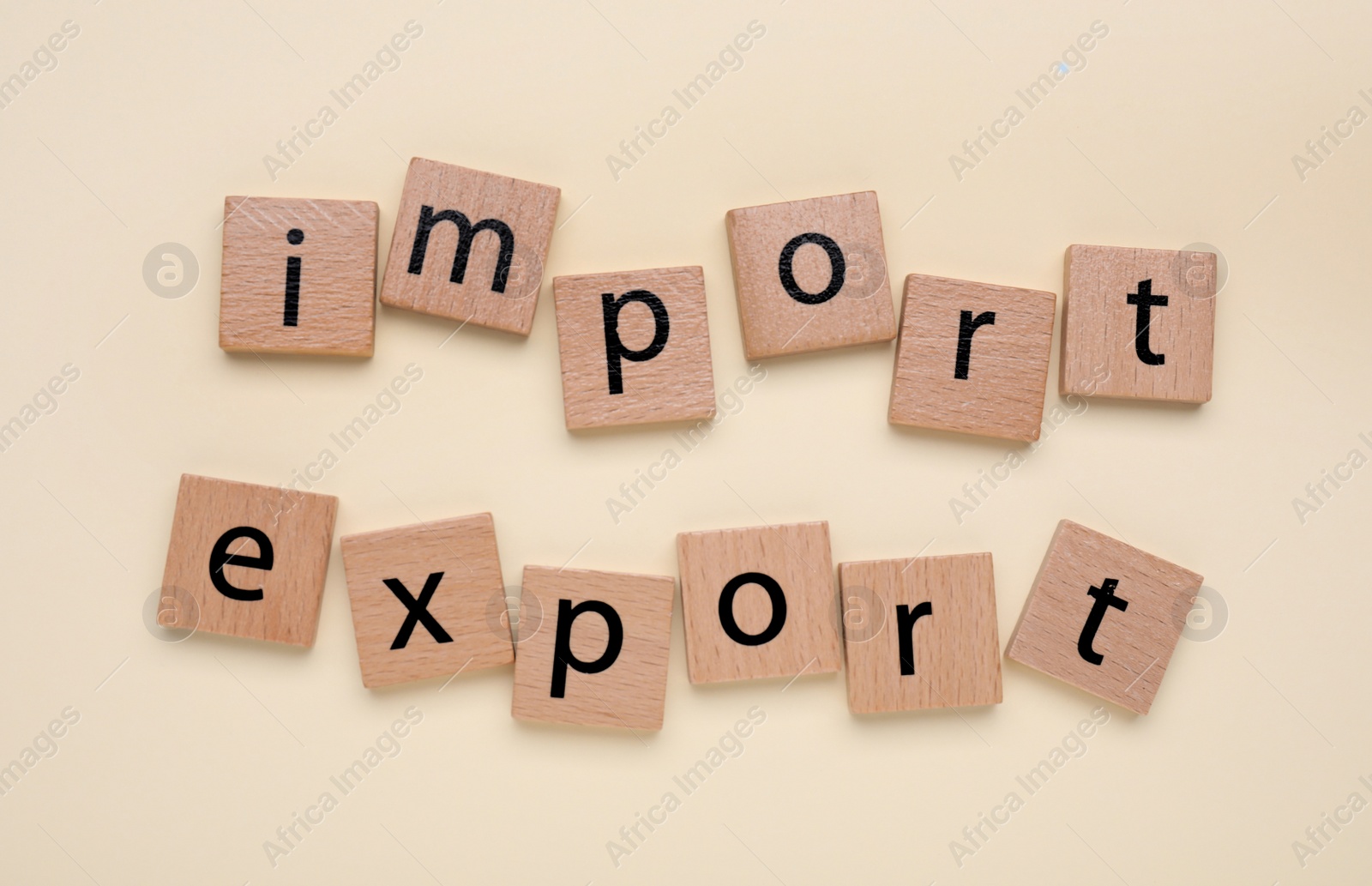 Photo of Words Import and Export made of wooden squares on beige background, top view