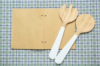 Blank recipe book and kitchen utensils on checkered tablecloth, flat lay. Space for text