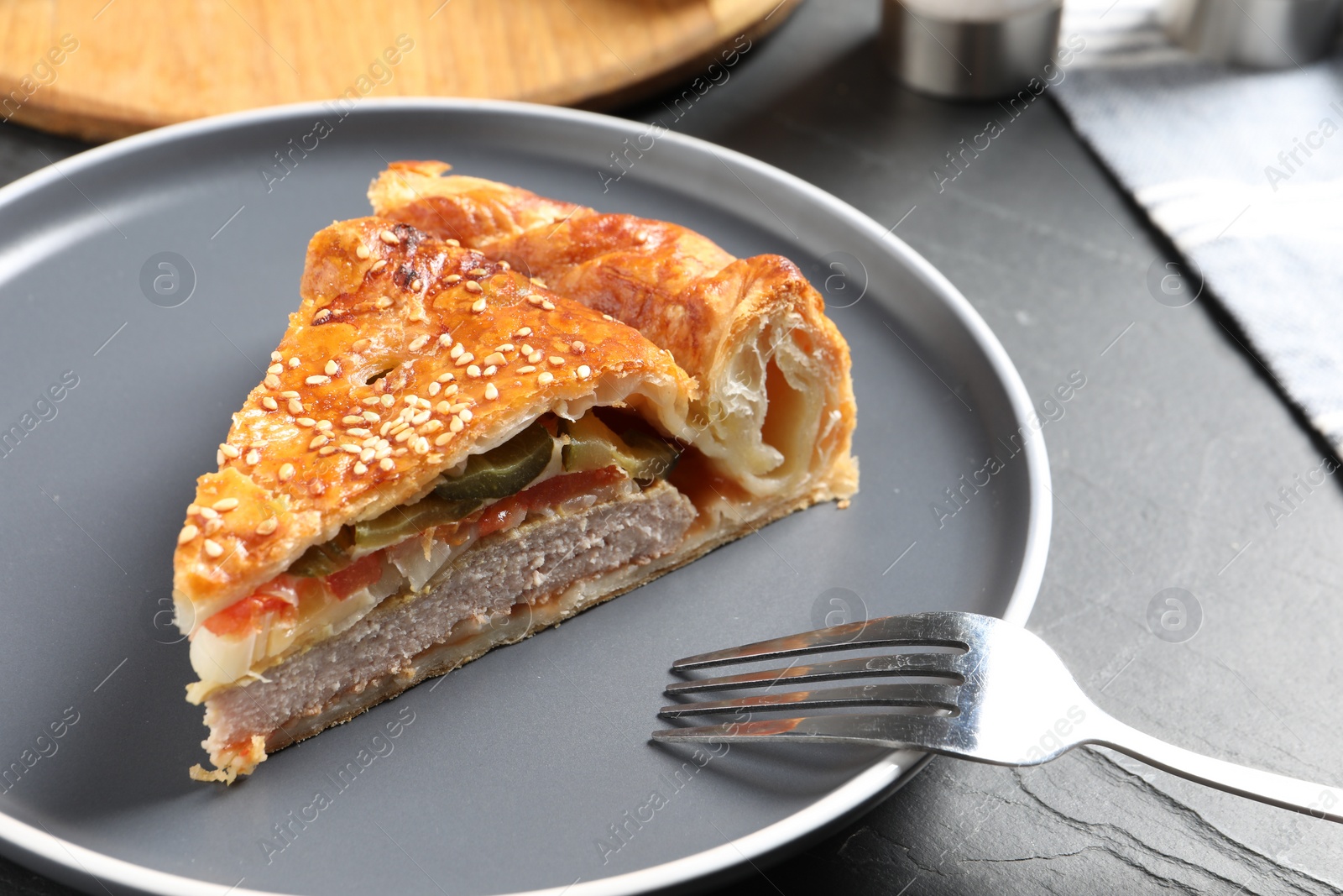 Photo of Piece of tasty homemade pie with filling on dark grey table