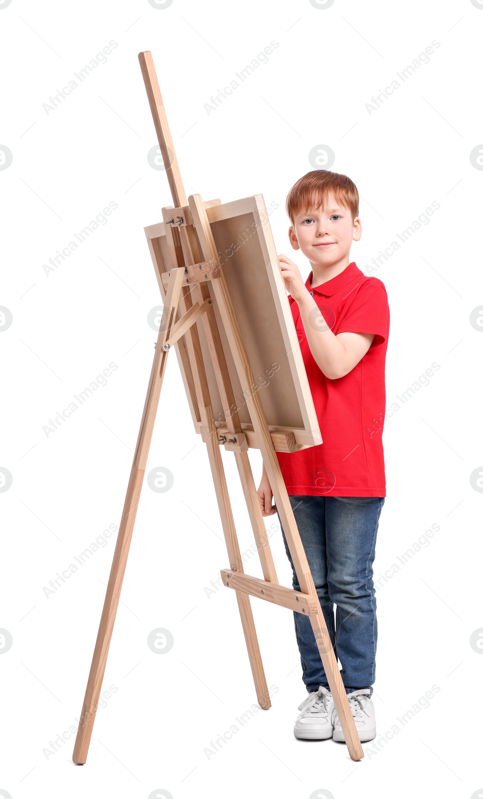 Photo of Little boy painting against white background. Using easel to hold canvas