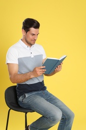 Photo of Handsome man reading book on color background