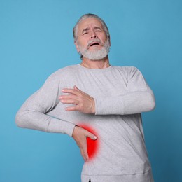 Senior man suffering from rheumatism on light blue background