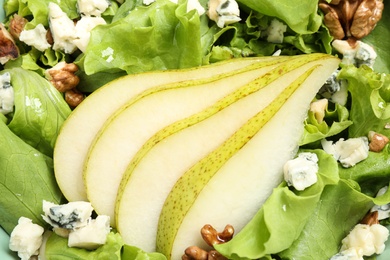 Tasty salad with pear slices as background, closeup