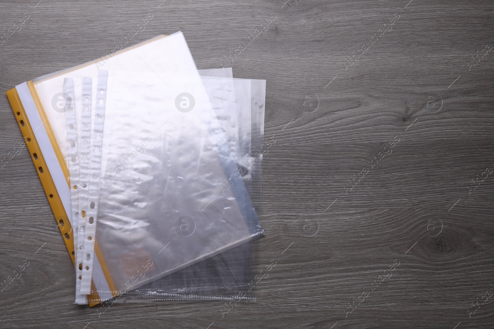 Photo of File folder with punched pockets on wooden table, flat lay. Space for text