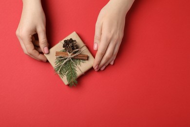 Photo of Woman with beautifully wrapped Christmas gift box on red background, top view. Space for text