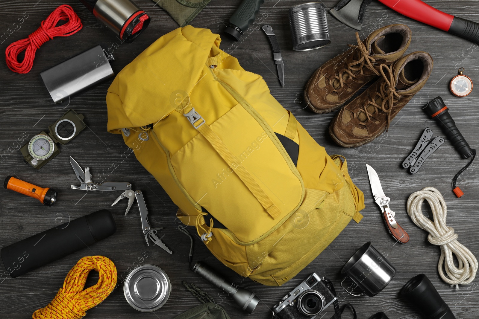 Photo of Flat lay composition with different camping equipment on dark wooden background. Traveler set