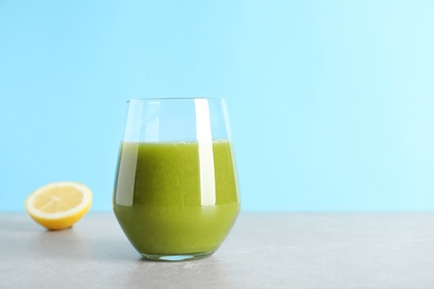 Glass with delicious detox juice and lemon on table