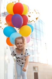 Photo of Cute little girl with colorful balloons outdoors on sunny day