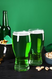 Photo of St. Patrick's day party. Green beer and pistachios on wooden table