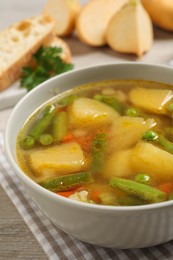 Photo of Bowl of delicious turnip soup on wooden table, closeup