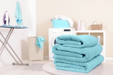 Stack of clean towels on table in laundry room. Space for text