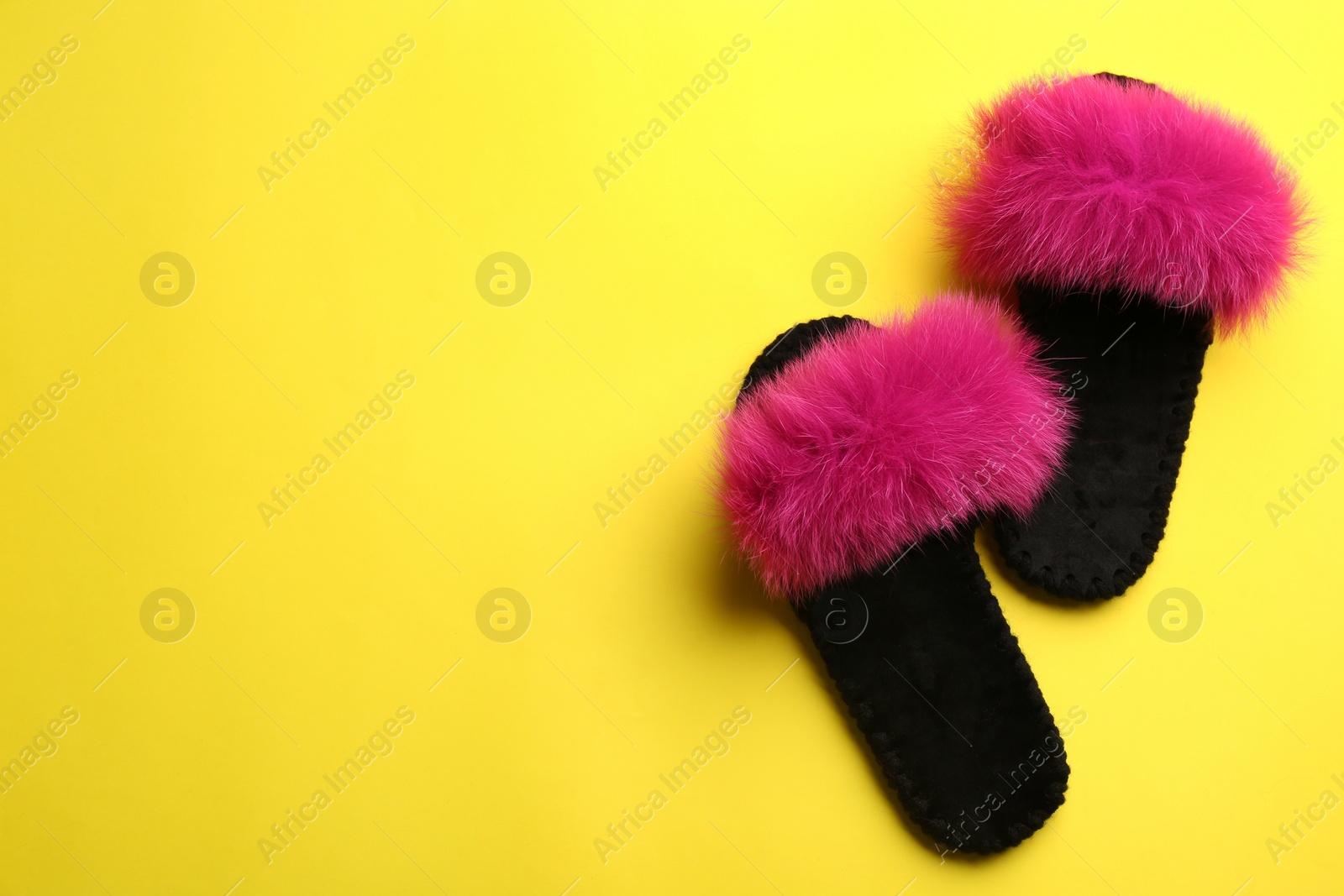 Photo of Pair of soft slippers on yellow background, flat lay. Space for text