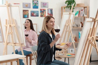 Photo of Women with glasses of wine attending painting class in studio. Creative hobby