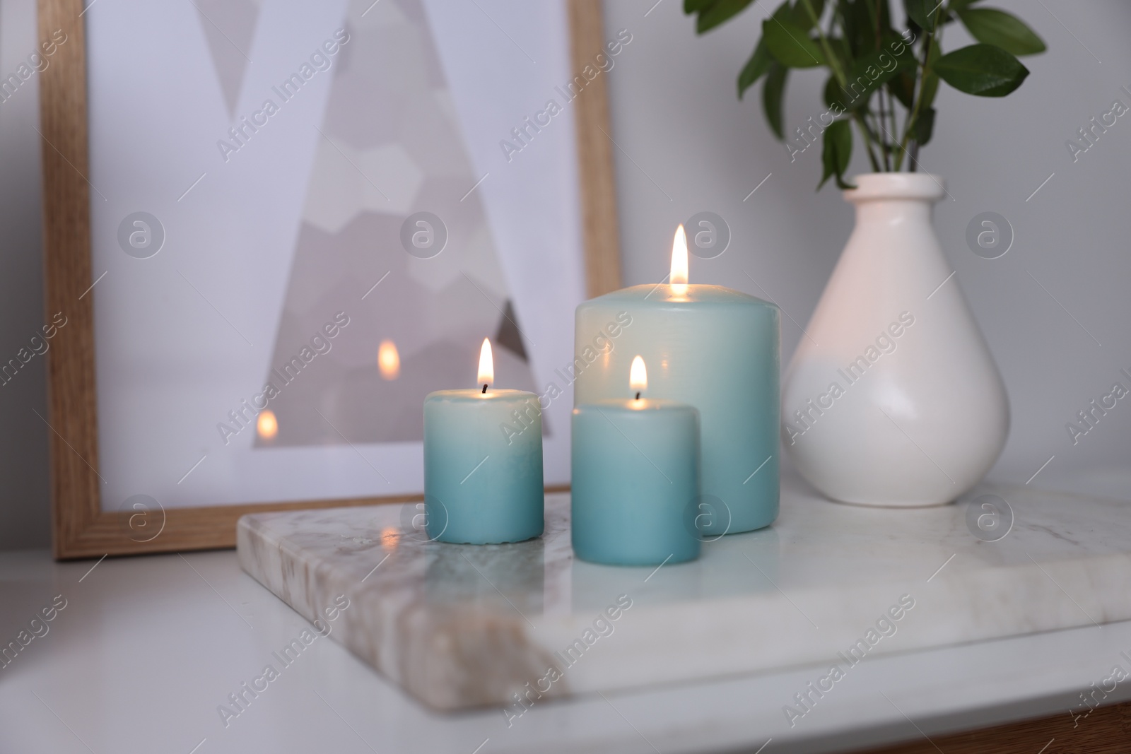 Photo of Burning candles and vase with green branches on white table