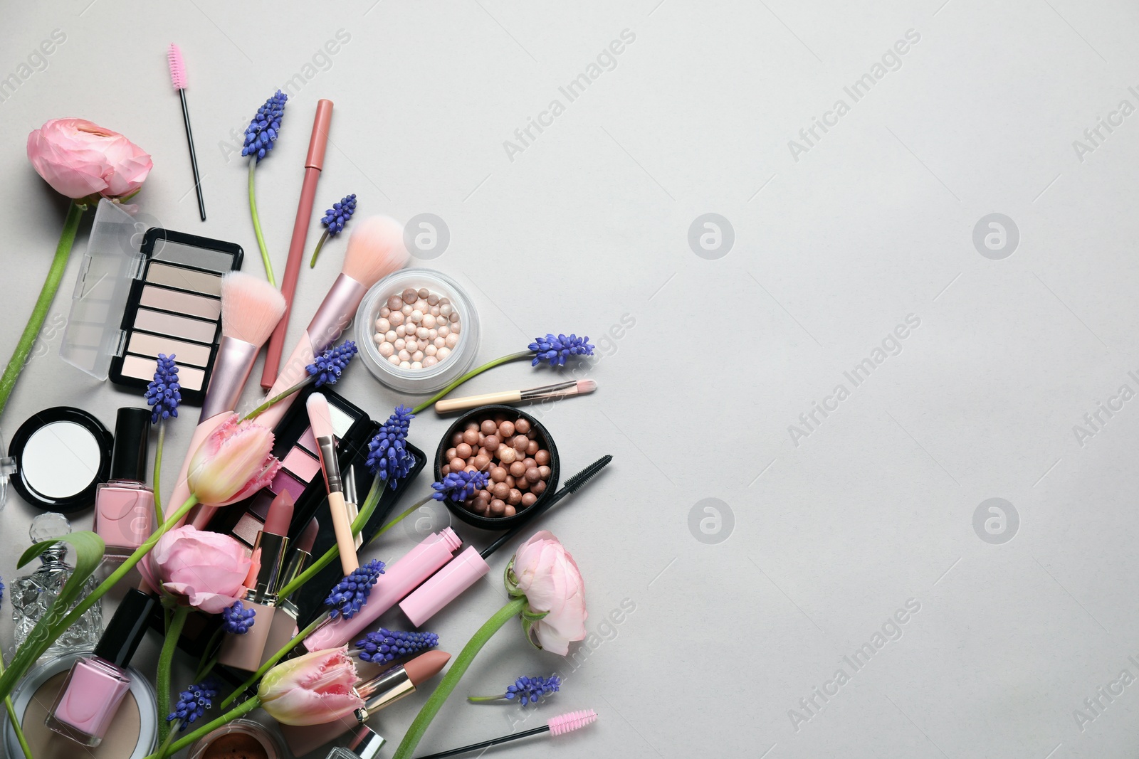 Photo of Flat lay composition with different makeup products and beautiful spring flowers on gray background, space for text