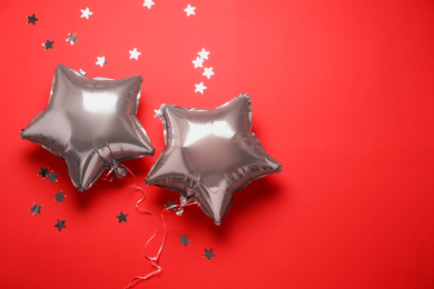 Star shaped pink balloons and confetti on red background, flat lay