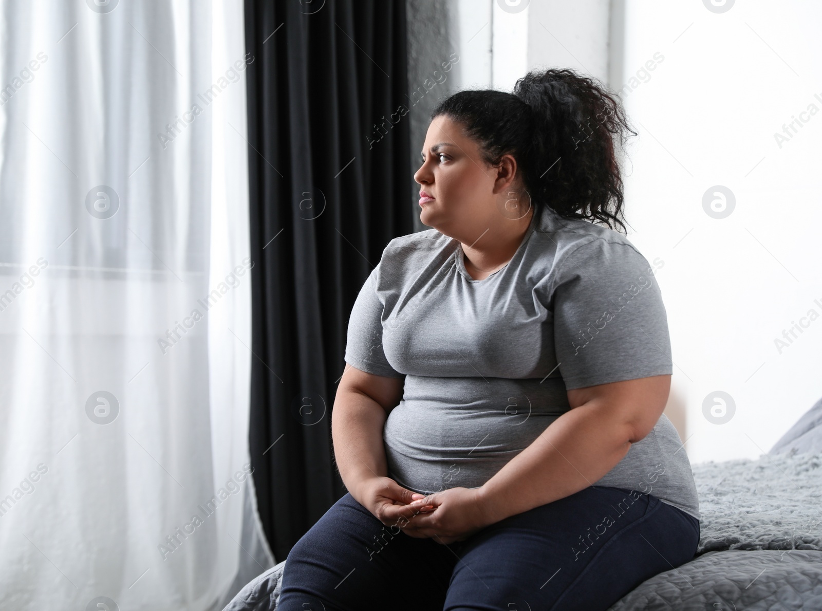 Photo of Depressed overweight woman on bed at home