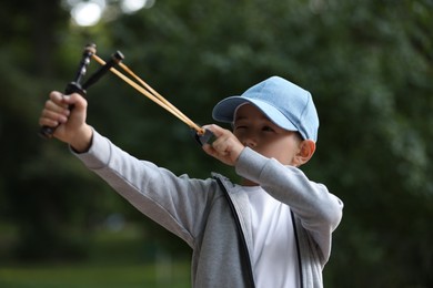 Little boy playing with slingshot in park