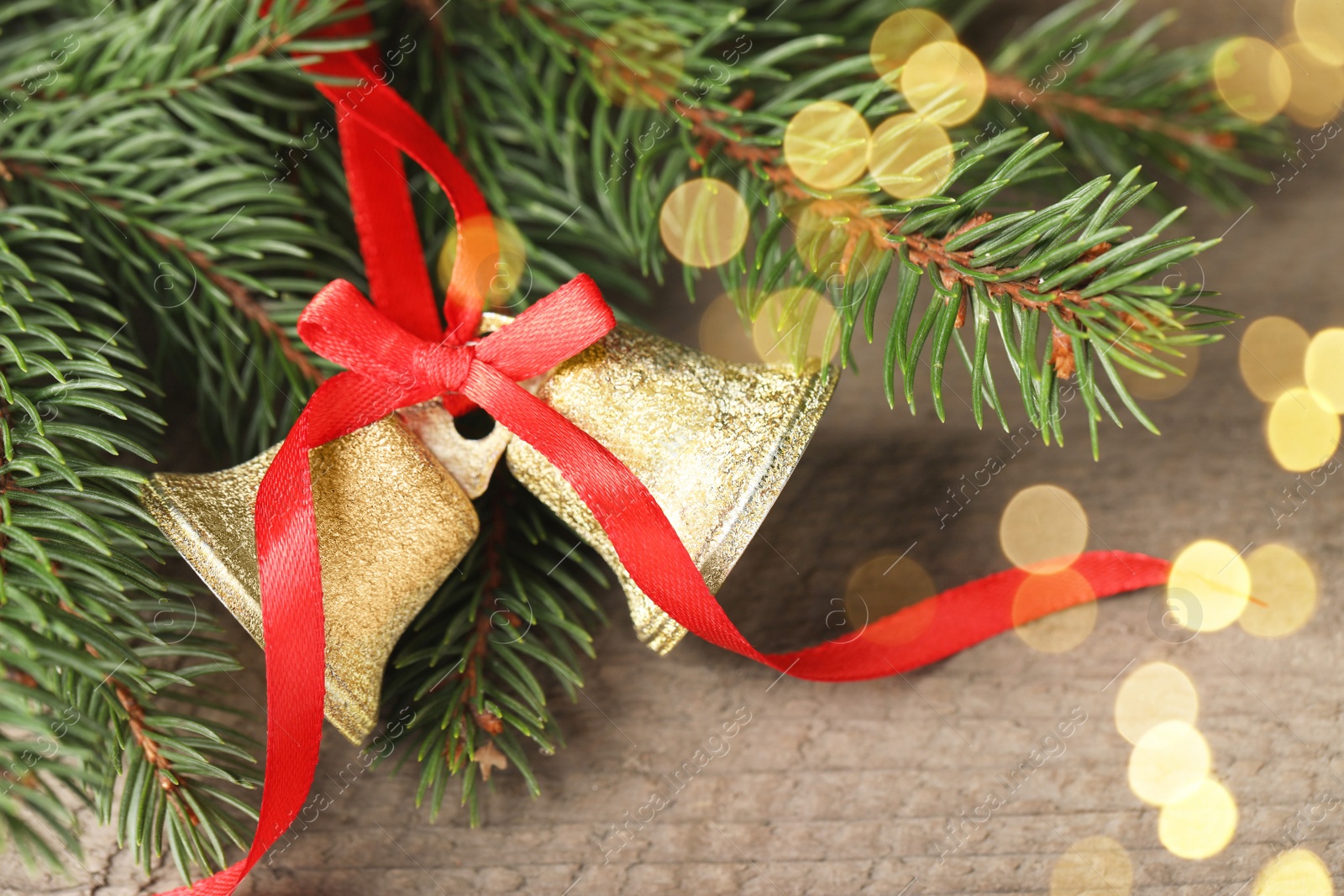 Photo of Bells and fir tree branches on wooden table, closeup. Christmas decor