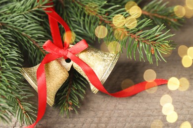 Photo of Bells and fir tree branches on wooden table, closeup. Christmas decor