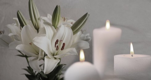 Image of Funeral. White lilies and burning candles on light grey background, banner design