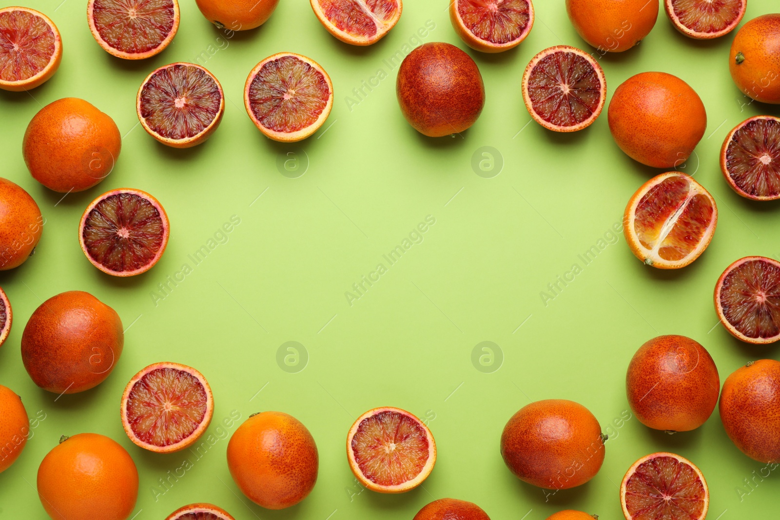 Photo of Frame of ripe sicilian oranges on light green background, flat lay. Space for text